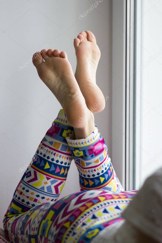 Home studio close up detailed shot of sexy beautiful female feet soles crossed with color indian style yoga pants.