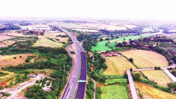 Widok z lotu ptaka na autostradę przez zielone pola w letni słoneczny dzień. Nagranie 4k krajobrazu z asfaltową autostradą pomiędzy łąkami. Drone nagrywa wideo — Wideo stockowe