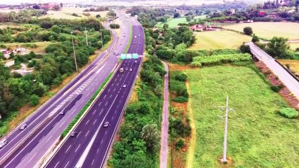 Widok z lotu ptaka na autostradę przez zielone pola w letni słoneczny dzień. Nagranie 4k krajobrazu z asfaltową autostradą pomiędzy łąkami. Drone nagrywa wideo — Wideo stockowe