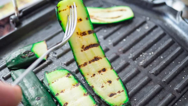 Grillowana cukinia na grillu z bliska. Zbliżenie rąk młodej kobiety. Skupienie selektywne — Zdjęcie stockowe