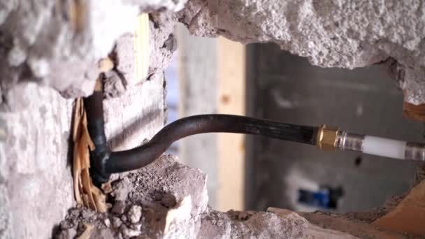 Instalación de nuevas tuberías de plástico en las puertas de la pared, trabajos de reparación en el suministro de agua. Tubos de fontanería para el suministro de agua en una pared de ladrillo gris durante la construcción y reparación — Vídeo de stock