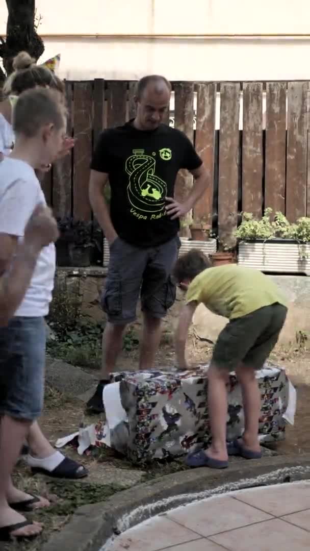 Rom Italien. Juni-21. 2020. Vertikales Video. Jungengeburtstag im Garten. Eltern helfen beim Auspacken der Geschenke
