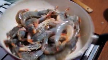 Karışık büyük kırmızı karidesler tavada kaynamış yağda kızartılıyor, yakın plan.