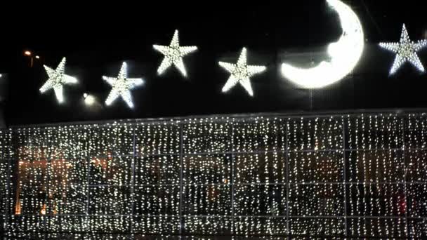 Decoración de la fiesta de Navidad: enorme estrella de oro y luna creciente hecha de lámparas incandescentes brillan brillantes en la oscuridad — Vídeo de stock