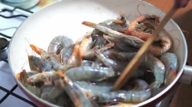 Kızarmış karidesler kızartma tavasını hazırlıyor. Karidesler savuruyor, karıştırıyor ve tavaya fırlatıyor, yavaş çekim yakın çekim.