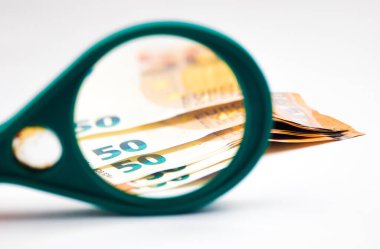 Beyaz arka planda büyüteç altında 50 avroluk banknotlar.