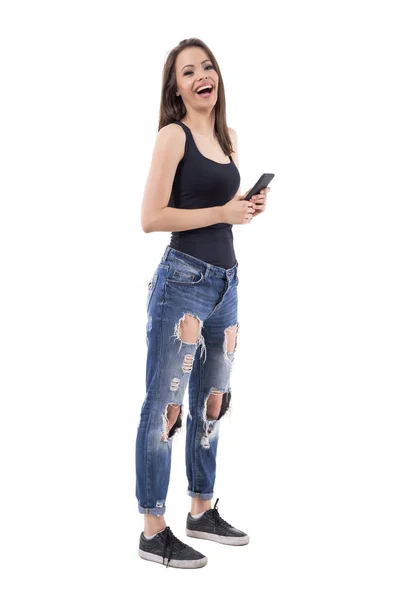 タンクトップとジーンズの携帯電話を保持していると笑っている美しい若い女性 全身白い背景に分離 — ストック写真