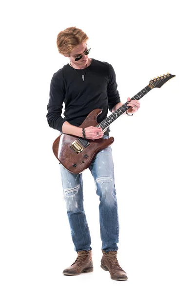 Cool relaxed young stylish handsome rocker man practicing or rehearsing electric guitar. Full body length isolated on white background.