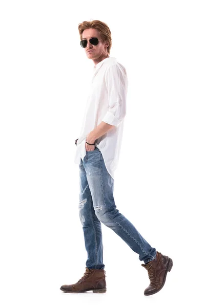 ポケットに手を入れて歩く本格的な支配的な若い町の男性のファッションモデルは カメラを見ています 白い背景に隔離された全身の長さ — ストック写真