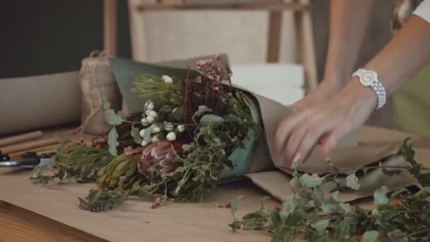 Floristería envolviendo ramo de flores en papel kraft — Vídeos de Stock
