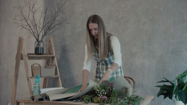 Жіночий флорист готує папір для упаковки квітів — стокове відео