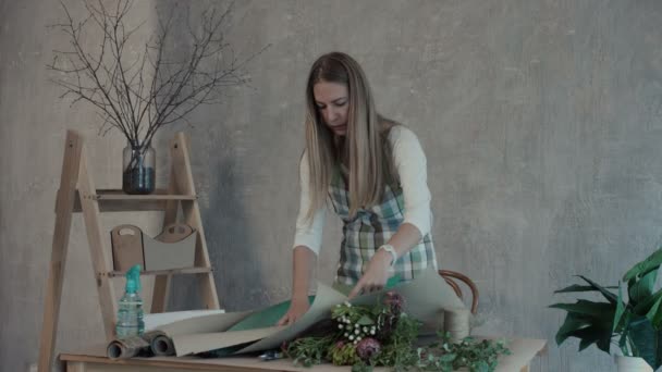 Floristería femenina prepara papel para el embalaje de flores — Vídeo de stock