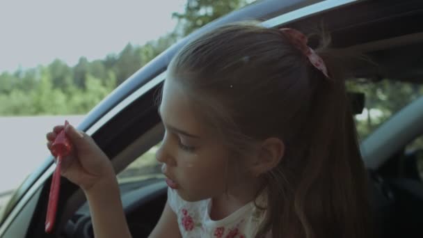 Schattig kind blazen van zeepbellen in de auto — Stockvideo