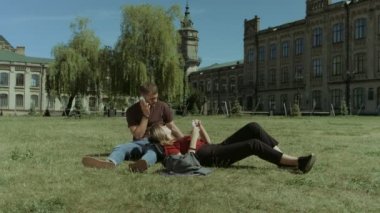 Üniversite öğrencileri kampüs çim üzerinde cep telefonu kullanarak