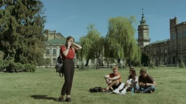 Kampüs çim akıllı telefonda konuşurken üniversiteli kız