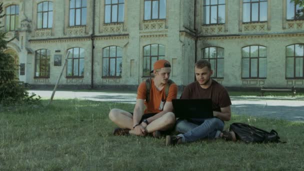 Estudiantes universitarios trabajando en portátil en el césped del campus — Vídeo de stock