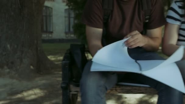 Studenten sitzen auf Bank und lernen mit Geräten — Stockvideo