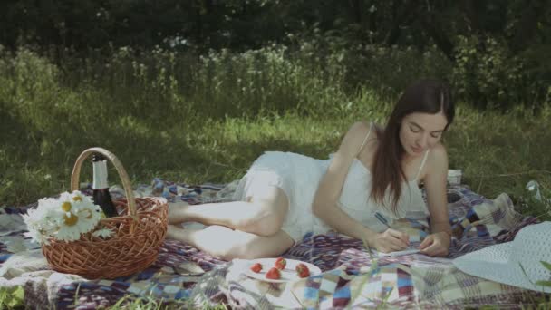 Продумана жінка робить нотатки в блокноті в парку — стокове відео