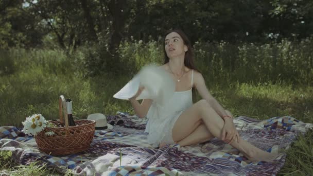 Женщина охлаждает себя шляпой в жаркий летний день — стоковое видео