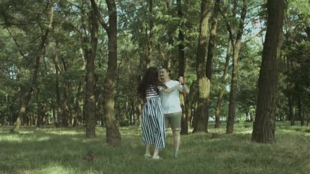 Счастливая беременная пара в любви танцует на природе — стоковое видео