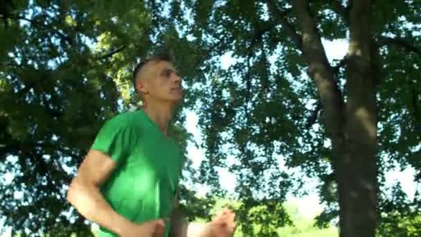 Athletic sporty young man jogging in public park — Stock Video