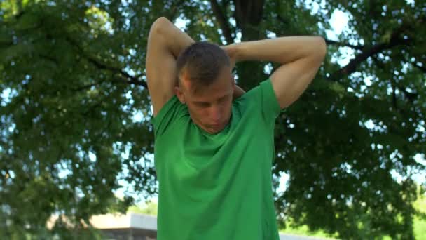 Healthy athletic man stretching arms and neck in park — Stock Video