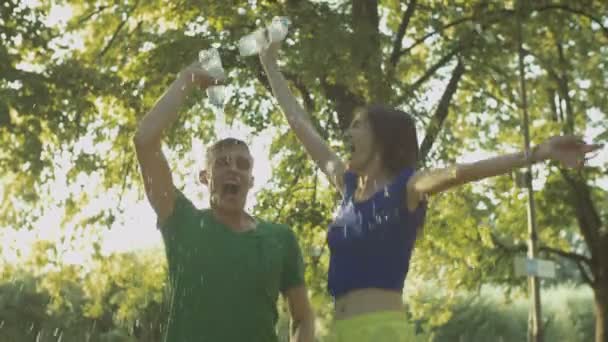 Emocionados corredores de pareja vertiendo agua sobre sí mismos — Vídeos de Stock
