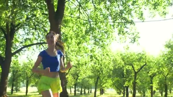 Sonriente hermosa mujer deportiva corriendo en el parque — Vídeo de stock