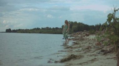 Plaj boyunca yürüyen neşeli Kızıl saçlı kadın