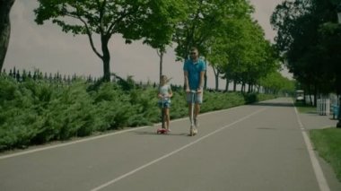 Neşeli baba ve kız parkta scooter sürme