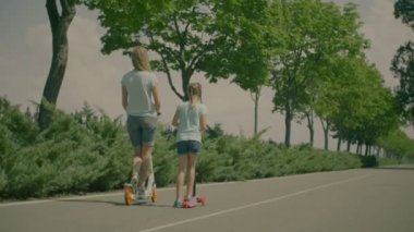 Güzel kız ve anne parkta eğleniyor scooter