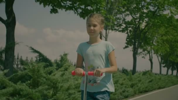 Niña disfrutando de su patada scooter paseo en el parque — Vídeos de Stock