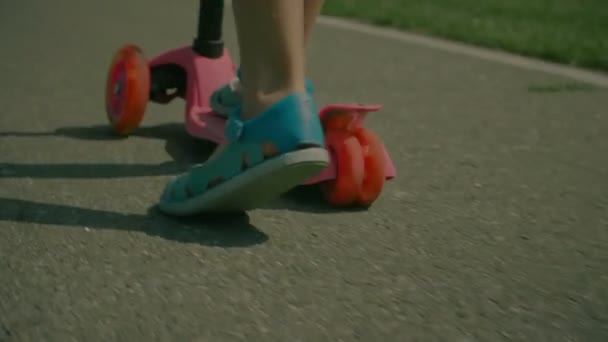 Childs voeten in sandalen duwen terwijl het berijden van de scooter — Stockvideo