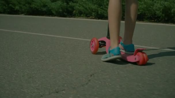 Feet of little girl in sandals riding push scooter — Stock Video