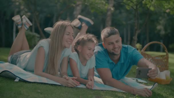 Família com criança fazendo selfie no cobertor ao ar livre — Vídeo de Stock