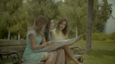 Mutlu traveler kadınlar bankta bir harita okuma