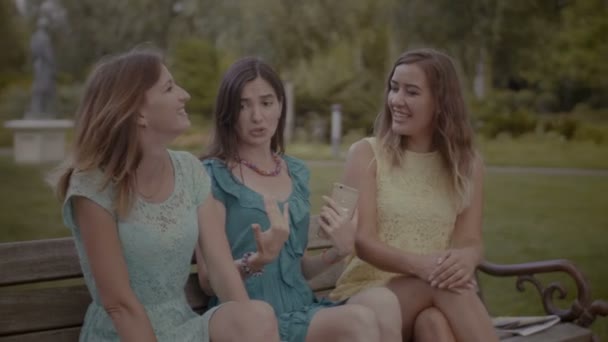 Прекрасные подруги сплетничают на скамейке — стоковое видео