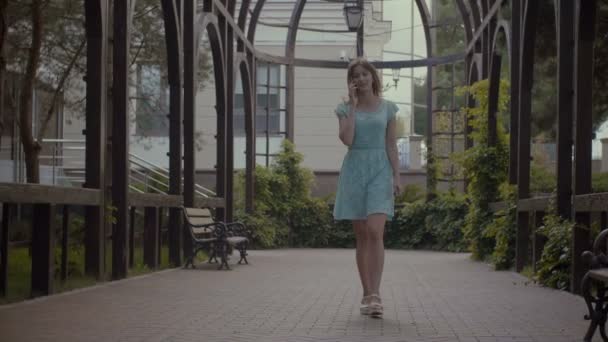 Девочка разговаривает по телефону во время прогулки на свежем воздухе — стоковое видео
