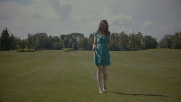 Χαρούμενη ξυπόλυτος γυναίκα το περπάτημα σε πράσινο χόρτο πεδίο — Αρχείο Βίντεο