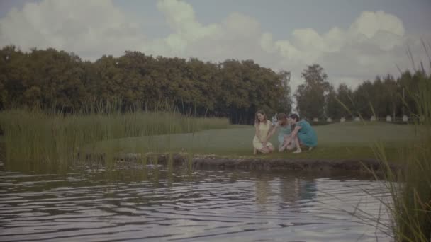 Mulheres relaxadas alimentando peixes na lagoa do parque — Vídeo de Stock