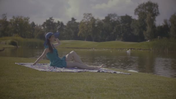 愉快的妇女在太阳帽子放松由湖 — 图库视频影像