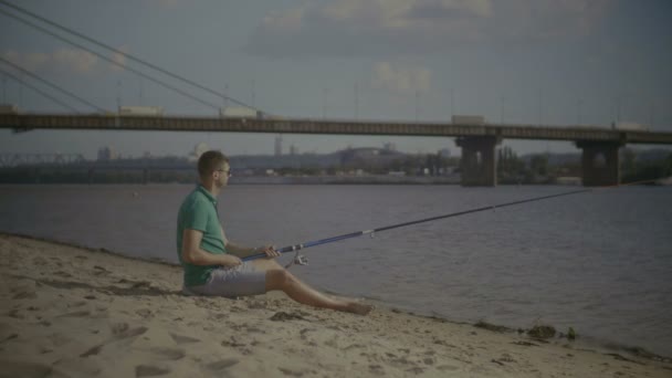 Relaxed man with spinning rod fishing on river — Stock Video