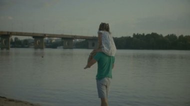 Babası onu omuzlarında taşıyan kızının oynarken