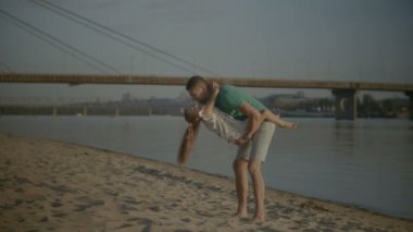 Baba ve kızı gün batımında sahilde oynarken