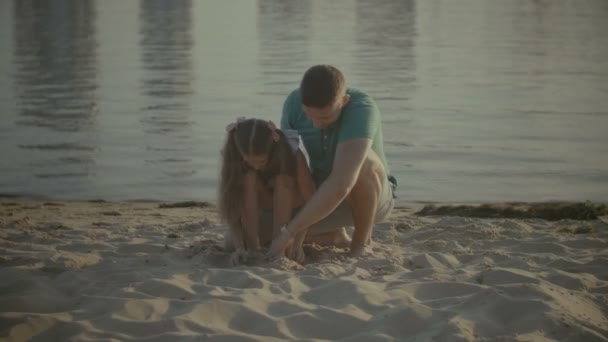 Vater und Tochter spielen im Sand am Strand — Stockvideo