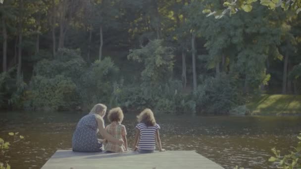 Härlig familj avkopplande på träbrygga vid damm — Stockvideo