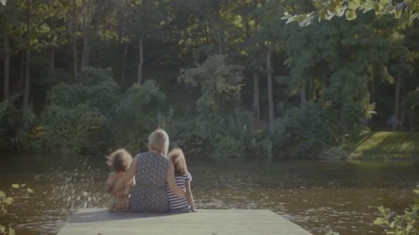 Familia feliz en amor abrazo descansando en muelle por lago — Vídeo de stock