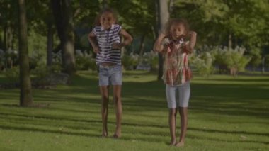 İki yaz Park yeşil çimenlerin üzerinde hip hop dans yalınayak Afro-Amerikan küçük kız gülümsüyor. Varoluş kıvırcık kız açık havada dans güzel doğal manzara arka plan üzerinde pratik.
