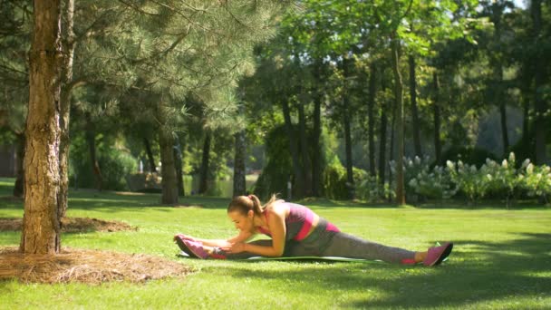 Fitness vrouw doen flexibiliteit oefeningen in park — Stockvideo