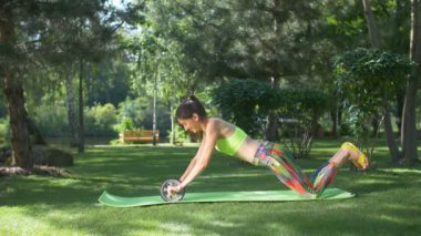 Gülümseyen kadın ab tekerlek tomar egzersiz yaparak uygun